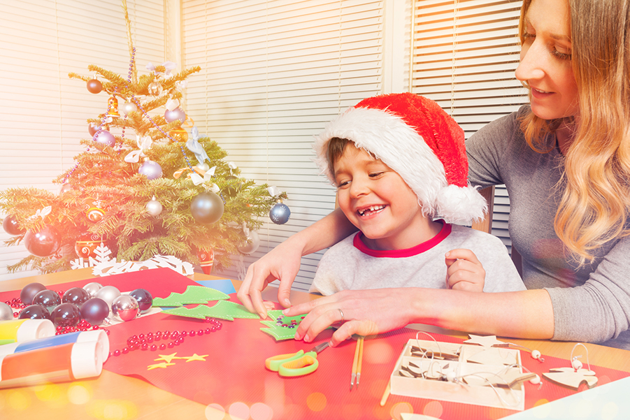 A mother helps her son make homemade Christmas gifts