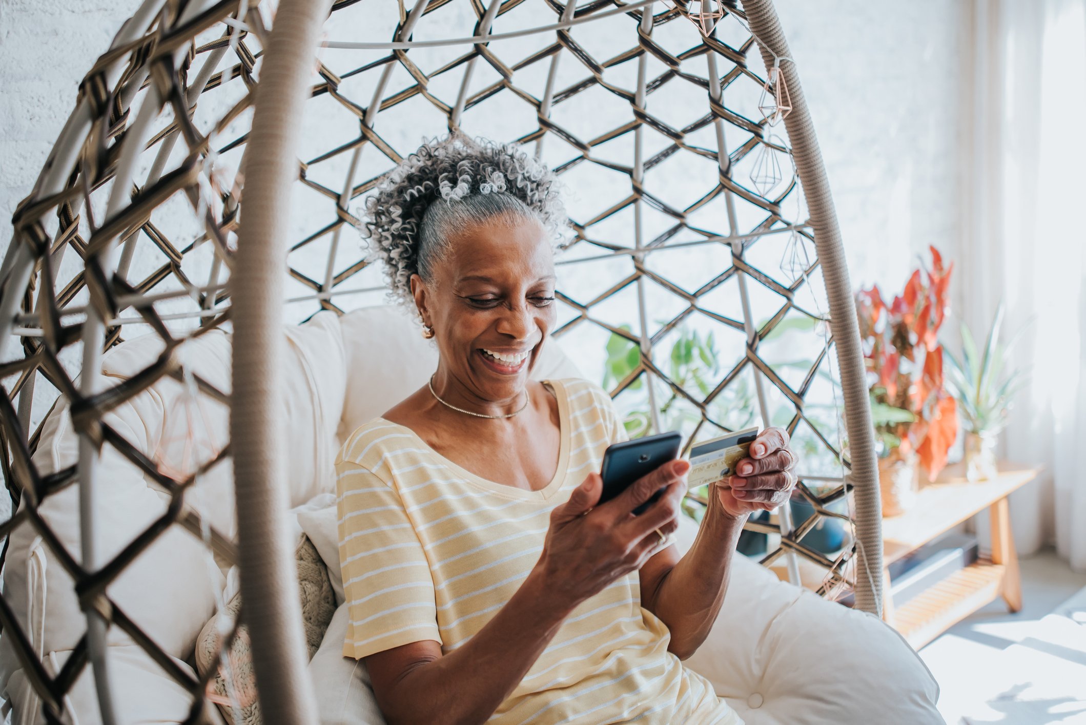 Woman smiles while holding a phone and credit card